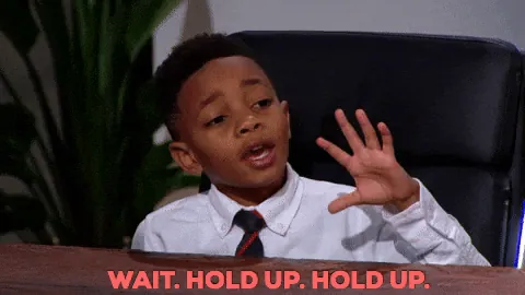 Kid at a desk holding his hand up: wait, hold up, hold up